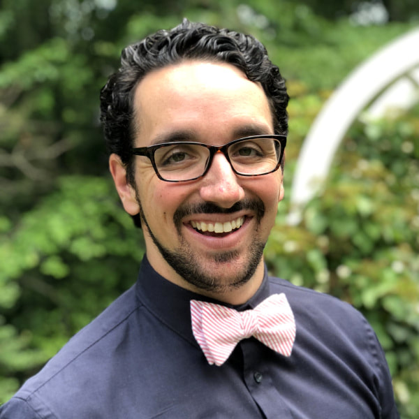 man with glasses, bowtie, and dark shirt, smiling
